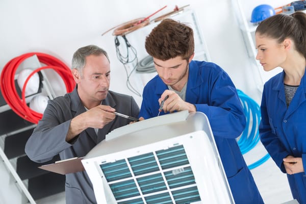 A master technician training apprentices on an HVAC system