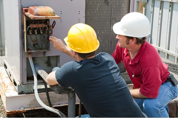 AC technicians repairing an industrial AC compressor