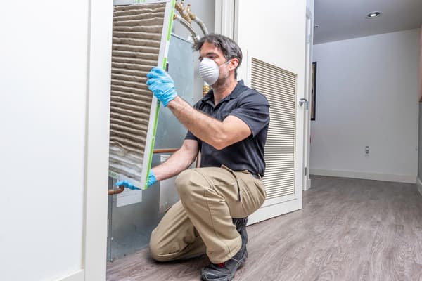 Hvac maintenance technician removing a dirty air filter from a heat pump