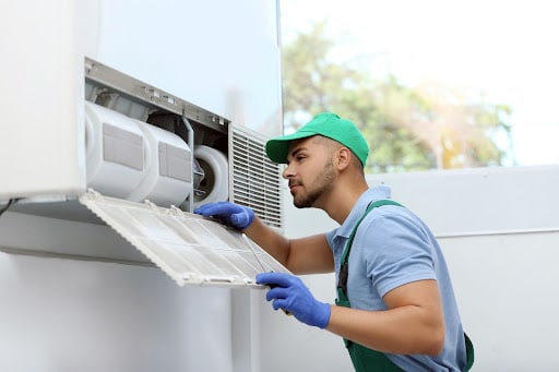 Professional technician maintaining modern air conditioner indoor